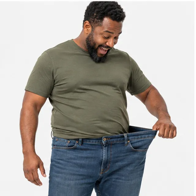 A smiling man holding out the loose waistband of his jeans