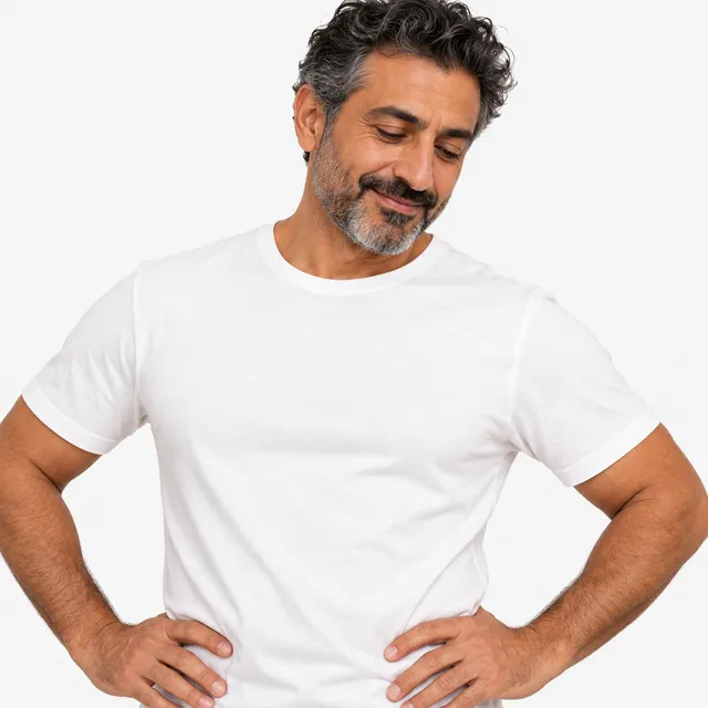 A smiling man in a white T-shirt with his hands on his hips