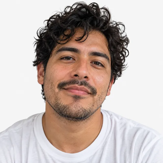 A man with curly dark hair and a moustache in a white T-shirt
