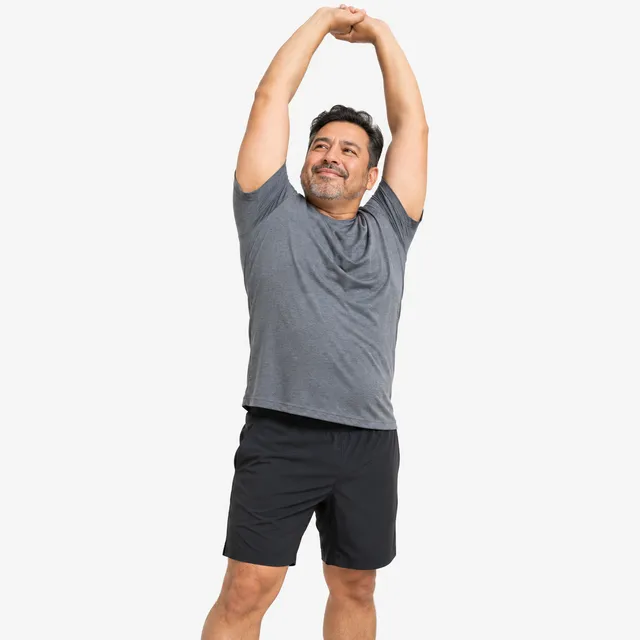 A smiling man stretching his arms overhead