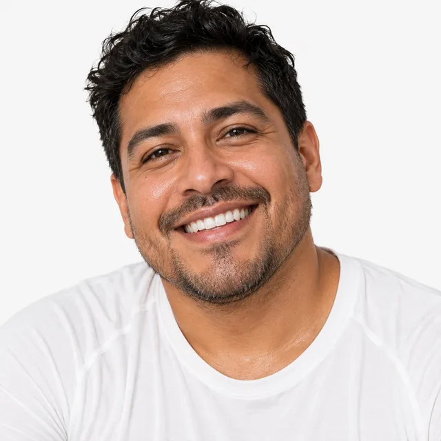 A smiling man with dark curly hair and a short beard in a white T-shirt