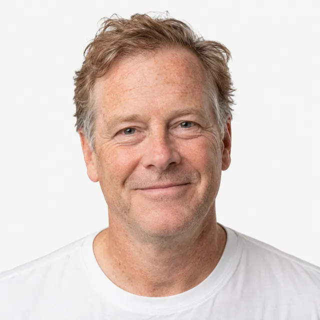 A smiling man with sandy, graying hair in a white T-shirt