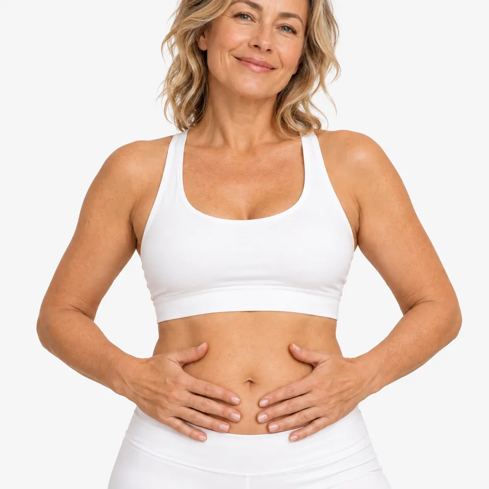 A smiling woman in white activewear with her hands on her stomach