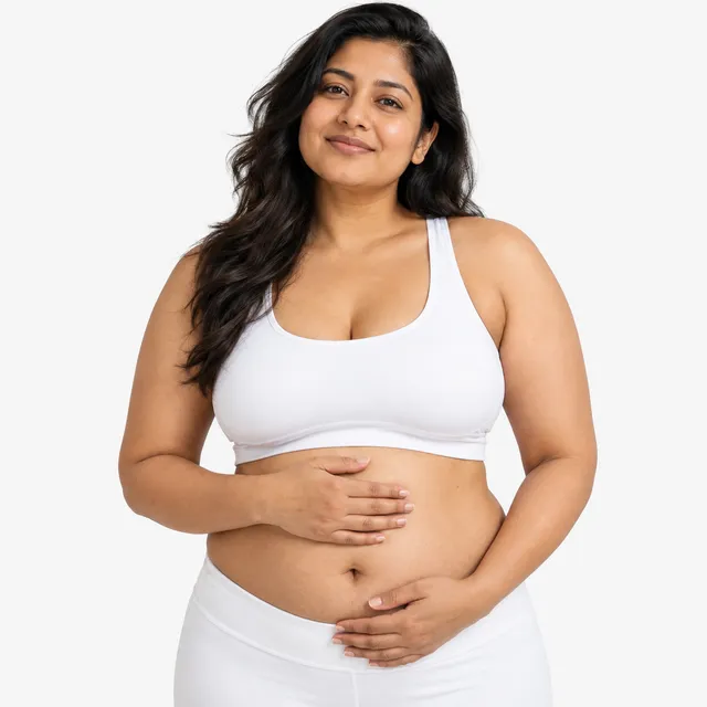 A smiling woman with long dark hair resting her hands on her stomach