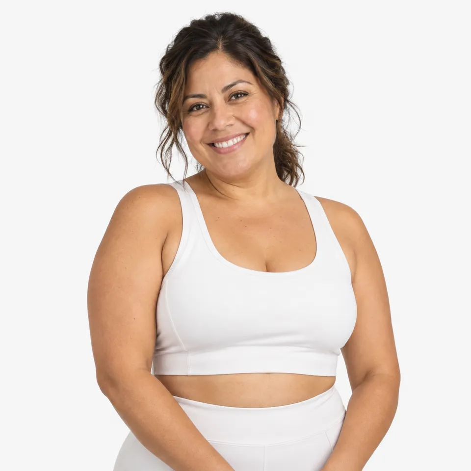 A smiling woman with dark curly hair in a white sports top