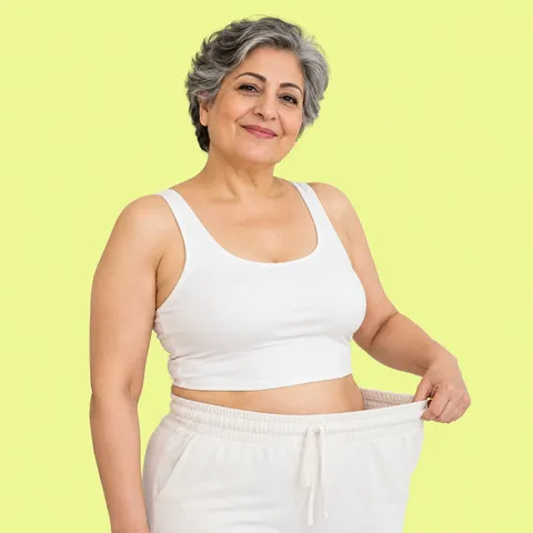 A smiling woman with gray hair holding out the loose waistband of her pants