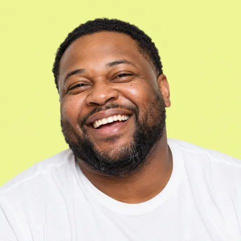 A laughing man with a beard in a white T-shirt