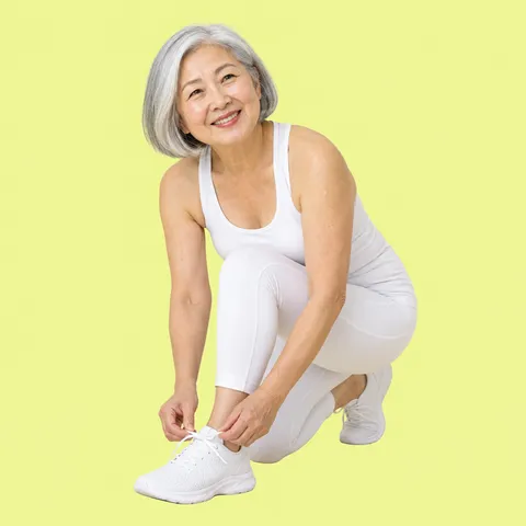 A smiling woman with gray hair tying her shoelace