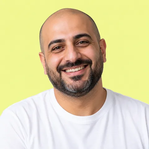A smiling bald man with a beard in a white T-shirt