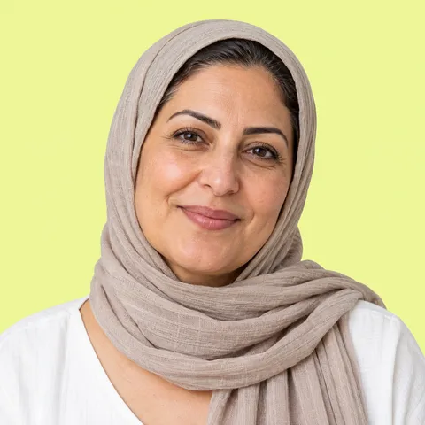 A smiling woman in a taupe hijab and a white top