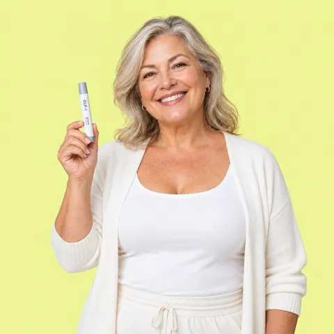 A smiling woman with fair hair holding up a GLP-1 injection pen