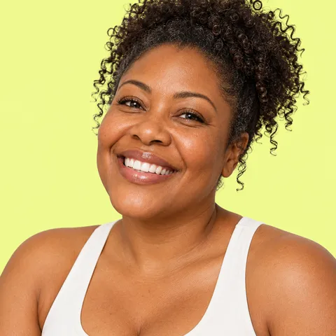 A smiling woman with curly hair tied up