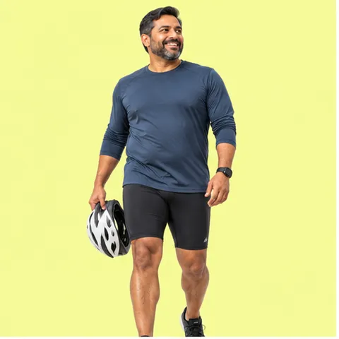 A smiling man in a navy top holding a cycling helmet